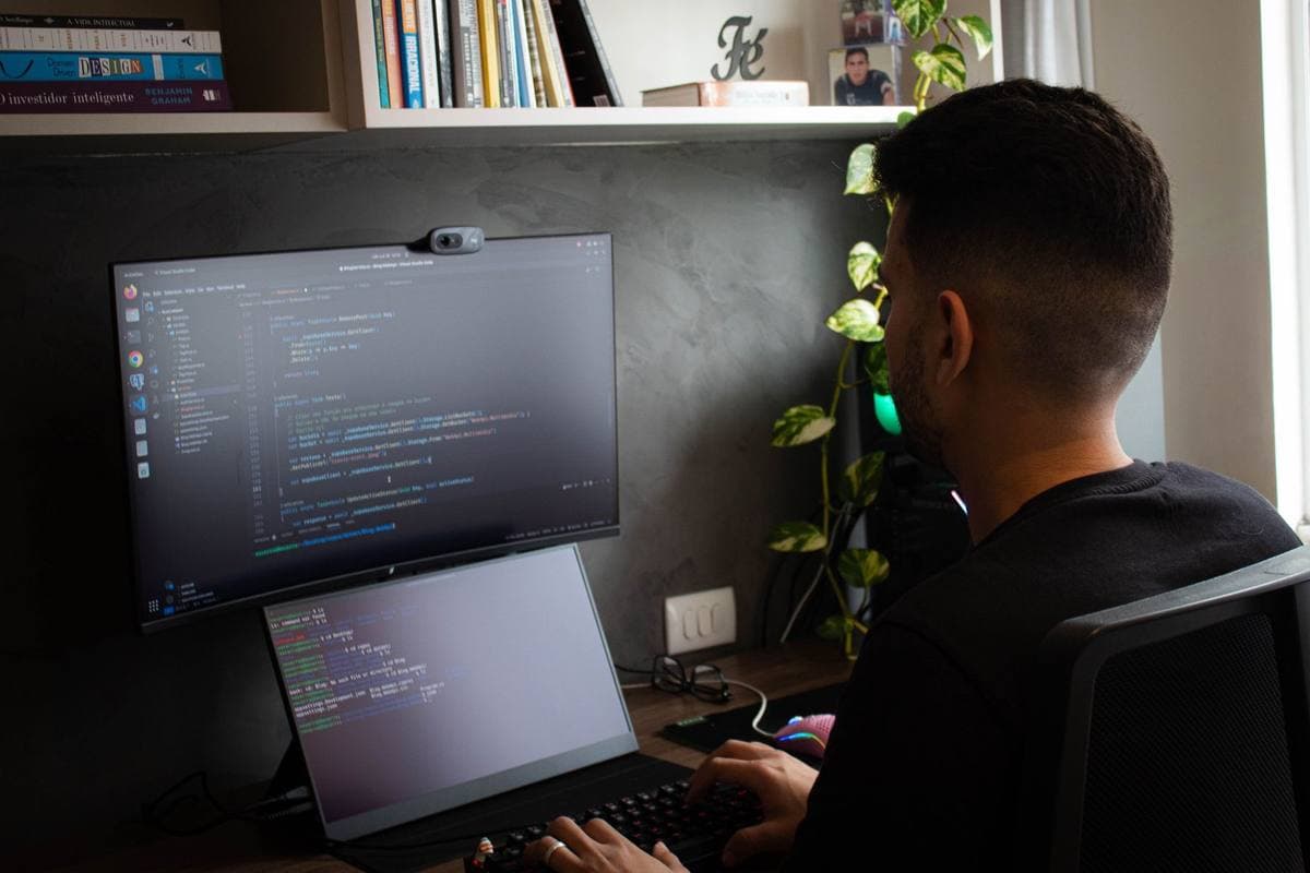 A developer at a desk with a monitor and a laptop showing code