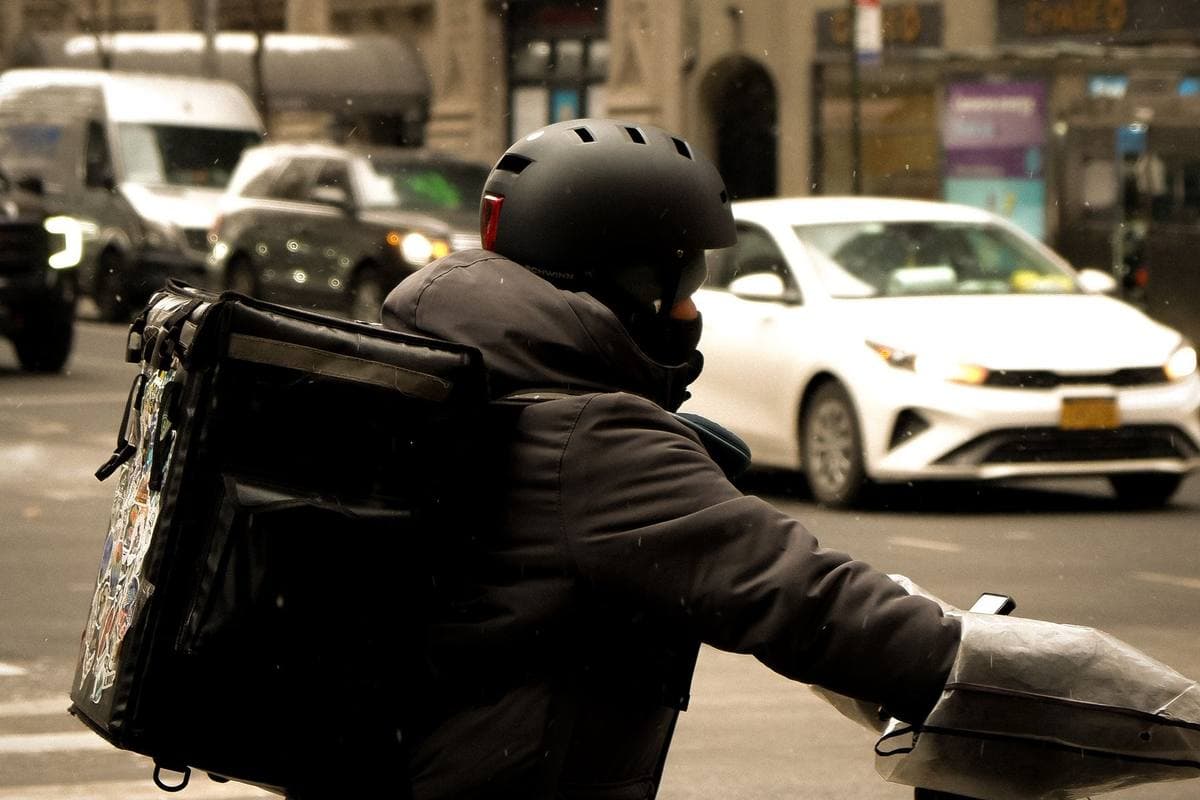 A delivery courier in a helmet with a thermal backpack on a city street